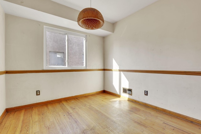 spare room with visible vents, wood-type flooring, and baseboards