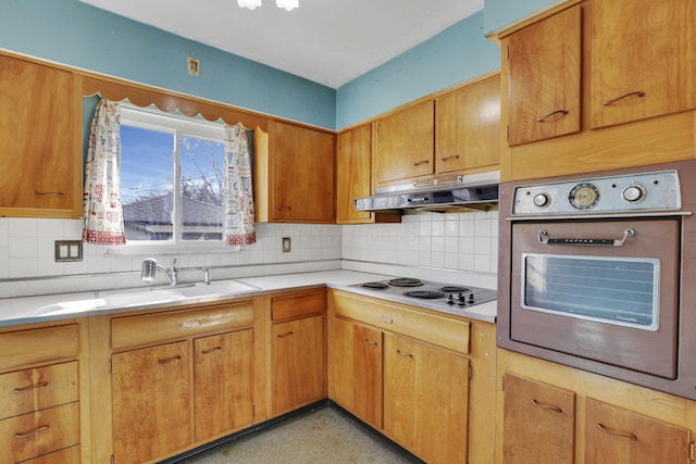 kitchen featuring under cabinet range hood, light countertops, stainless steel oven, electric stovetop, and a sink