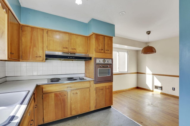 kitchen with visible vents, backsplash, oven, under cabinet range hood, and electric stovetop