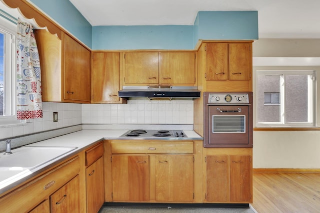 kitchen with under cabinet range hood, electric cooktop, wall oven, and decorative backsplash