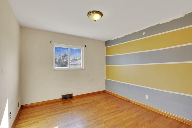 unfurnished room featuring visible vents, baseboards, and wood finished floors