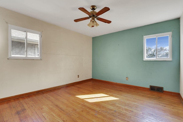 spare room featuring plenty of natural light, light wood-style floors, visible vents, and baseboards