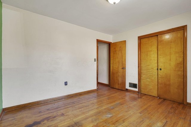 unfurnished bedroom featuring visible vents, baseboards, light wood-style floors, and a closet