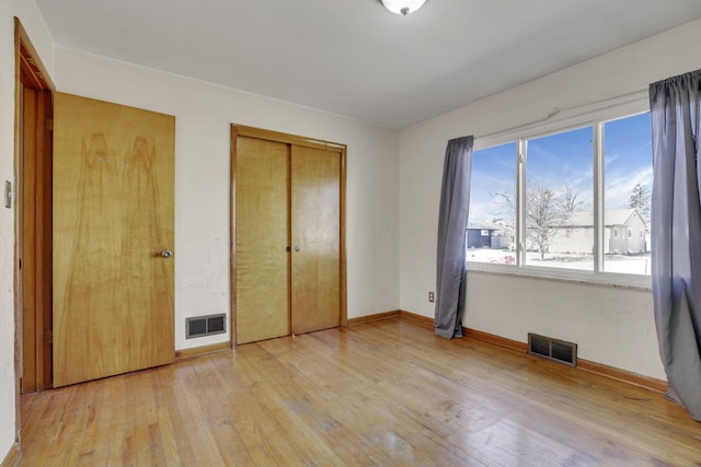 unfurnished bedroom with visible vents, baseboards, light wood-style floors, and a closet