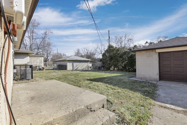 view of yard featuring a garage, a patio, central AC, and an outdoor structure