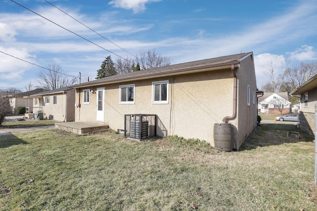 rear view of house with stucco siding and a yard