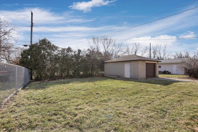 view of yard featuring an outbuilding, fence, a garage, and driveway