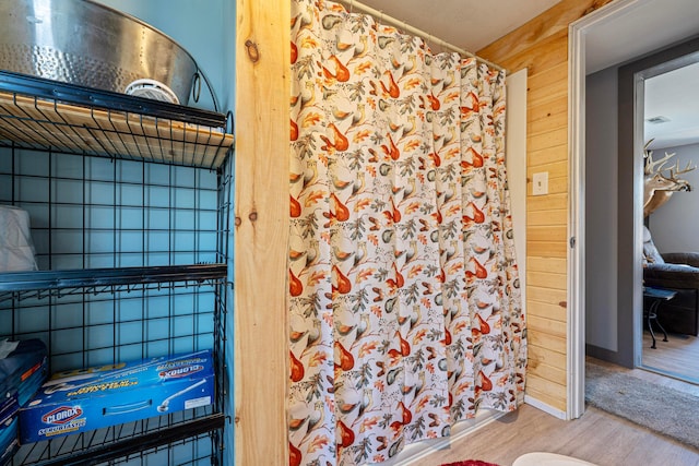 bathroom featuring a shower with curtain, wood finished floors, and wood walls