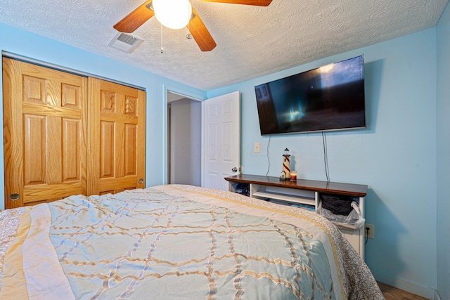 bedroom featuring visible vents, baseboards, ceiling fan, a closet, and a textured ceiling