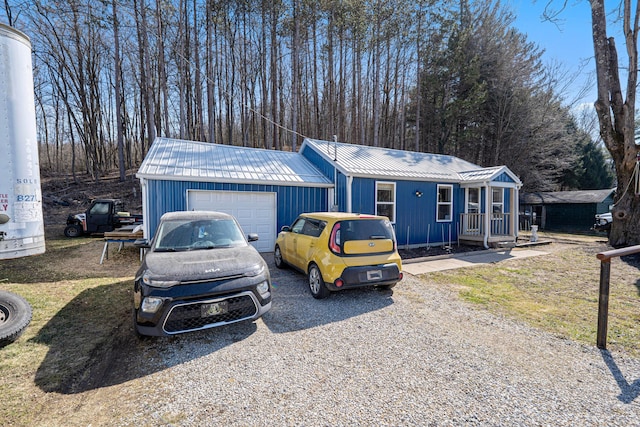 view of front of home featuring gravel driveway, a garage, and metal roof