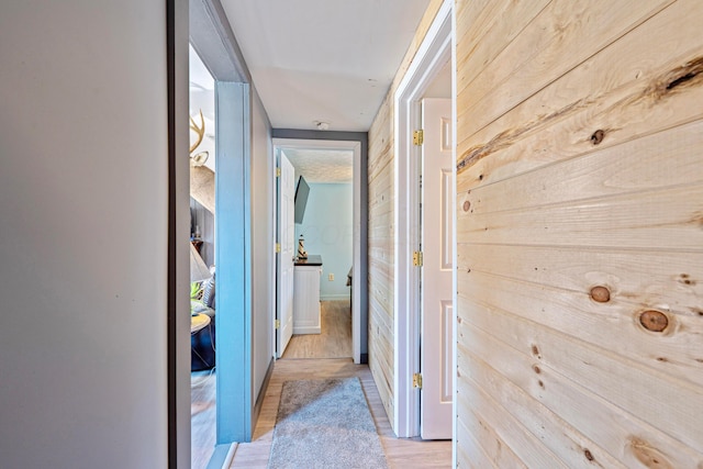 corridor with wood walls and light wood-type flooring