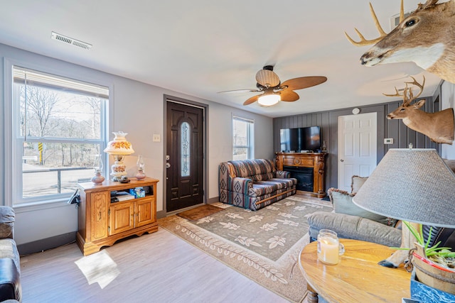 living room featuring light wood-style flooring, visible vents, and a wealth of natural light