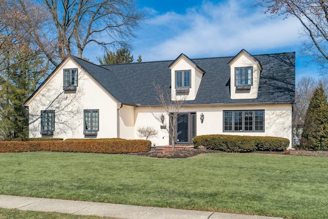 view of front facade featuring a shingled roof, a front lawn, and stucco siding