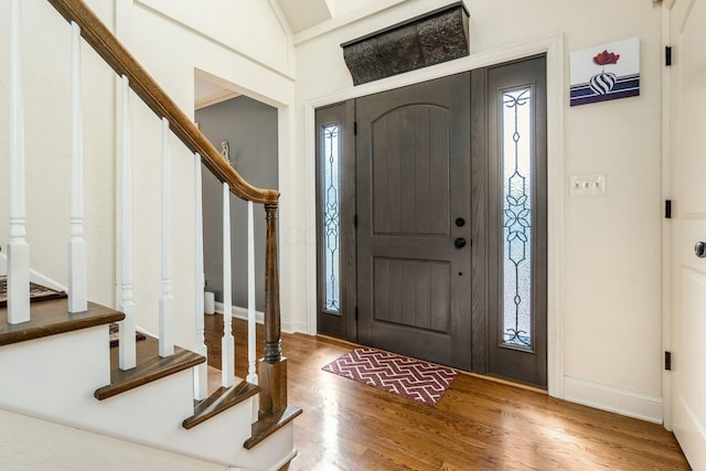 foyer with stairway, baseboards, and wood finished floors