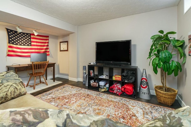 living area featuring rail lighting, a textured ceiling, baseboards, and wood finished floors