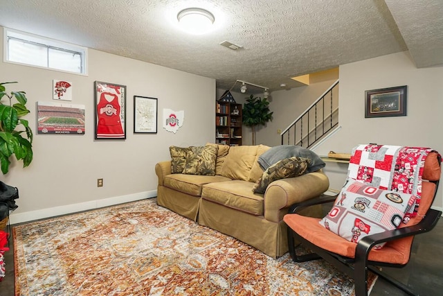 living area featuring stairway, visible vents, and a textured ceiling