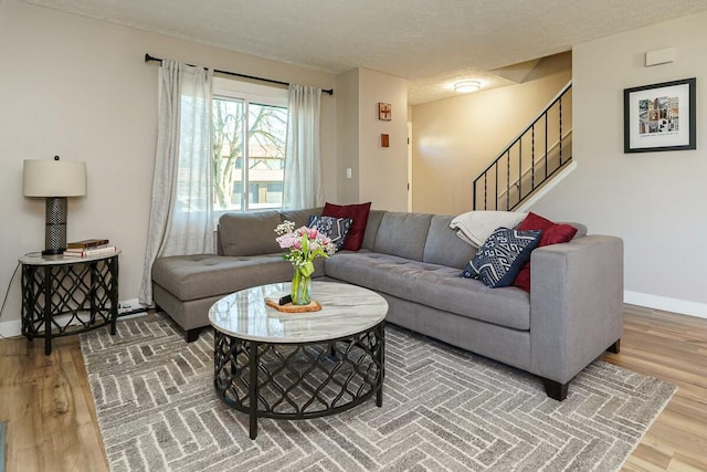 living room with baseboards, a textured ceiling, wood finished floors, and stairs