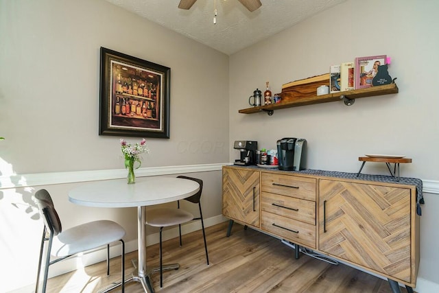 bar with a textured ceiling, wood finished floors, and a ceiling fan