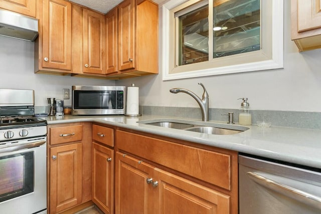 kitchen featuring under cabinet range hood, light countertops, appliances with stainless steel finishes, and a sink