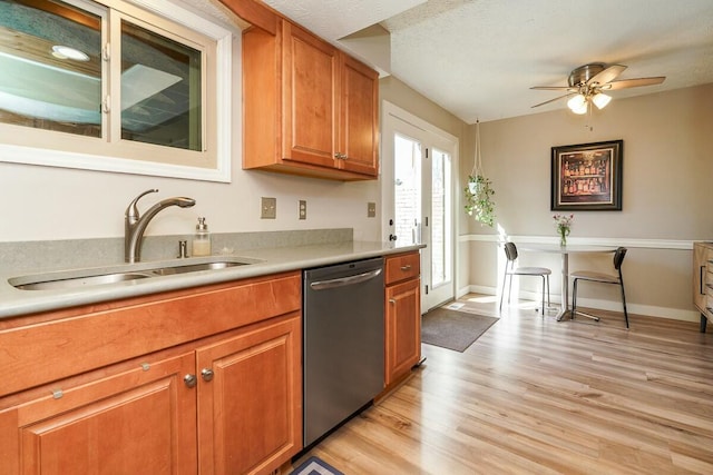 kitchen with brown cabinetry, a sink, light countertops, light wood-style floors, and dishwasher