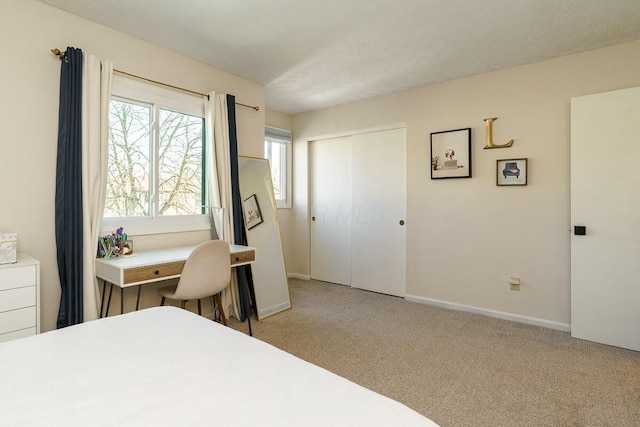 bedroom with light colored carpet, baseboards, a closet, and a textured ceiling