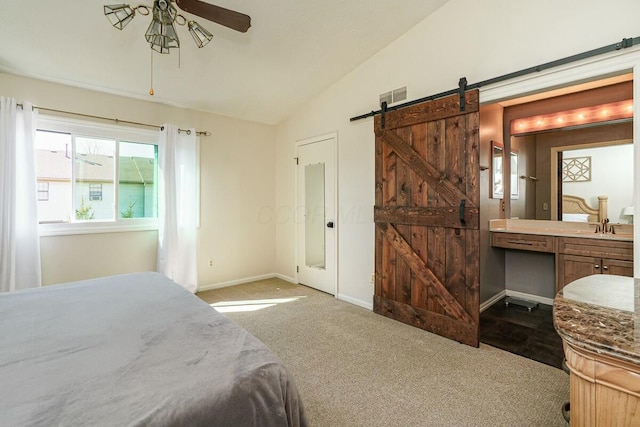 carpeted bedroom with visible vents, lofted ceiling, a barn door, connected bathroom, and baseboards