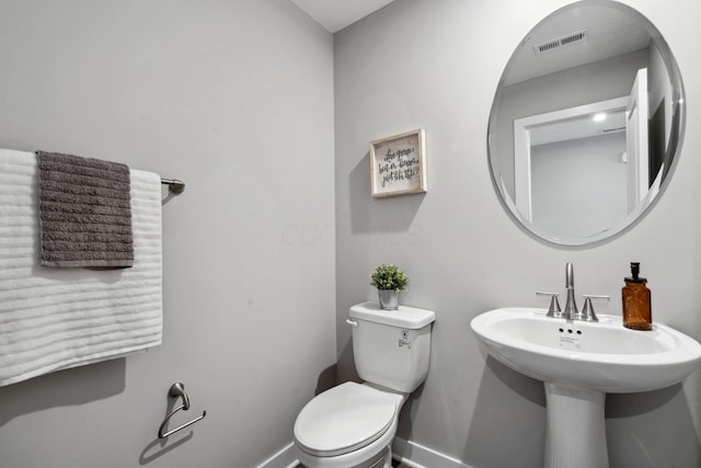 bathroom featuring toilet, baseboards, visible vents, and a sink