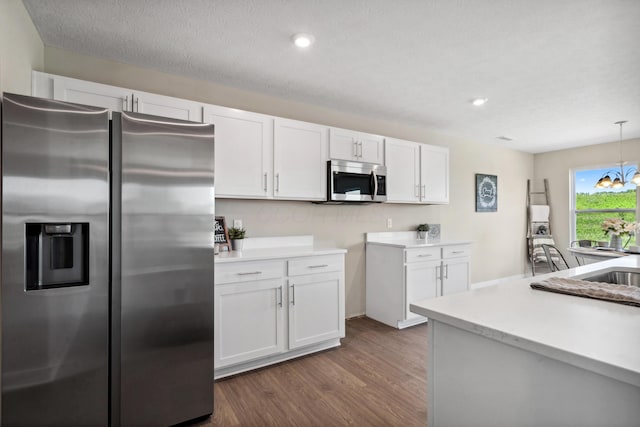 kitchen with dark wood finished floors, decorative light fixtures, light countertops, appliances with stainless steel finishes, and white cabinets