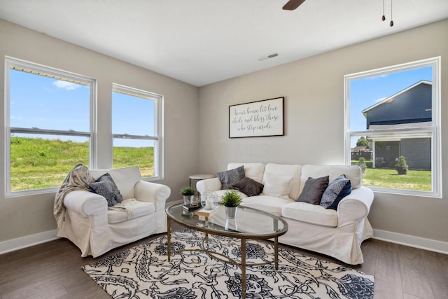 living area with a ceiling fan, wood finished floors, visible vents, and baseboards