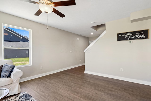 sitting room featuring ceiling fan, stairway, baseboards, and wood finished floors