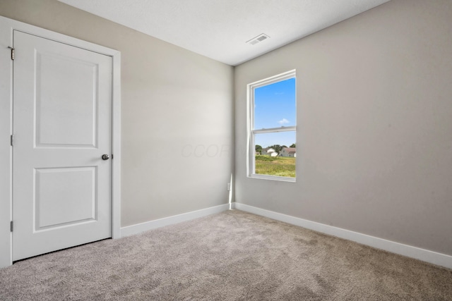 carpeted spare room with visible vents and baseboards