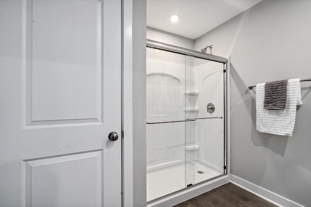 full bathroom featuring a shower stall, baseboards, and wood finished floors