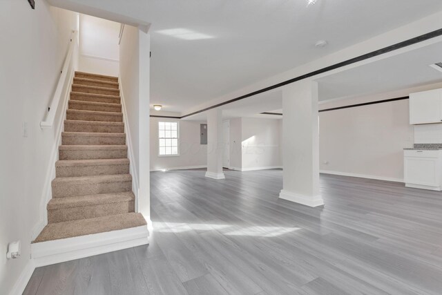 interior space featuring electric panel, baseboards, and wood finished floors