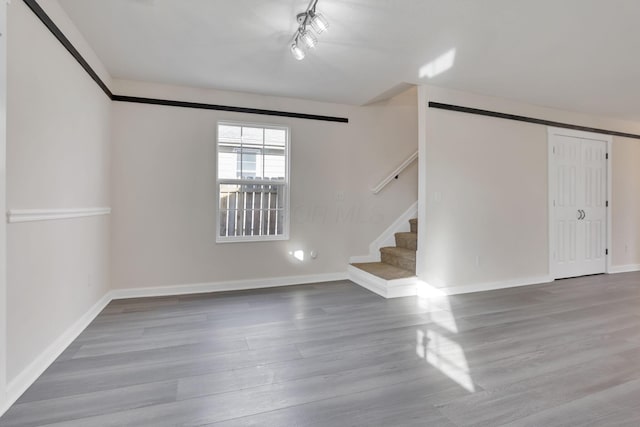 empty room featuring stairway, baseboards, and wood finished floors