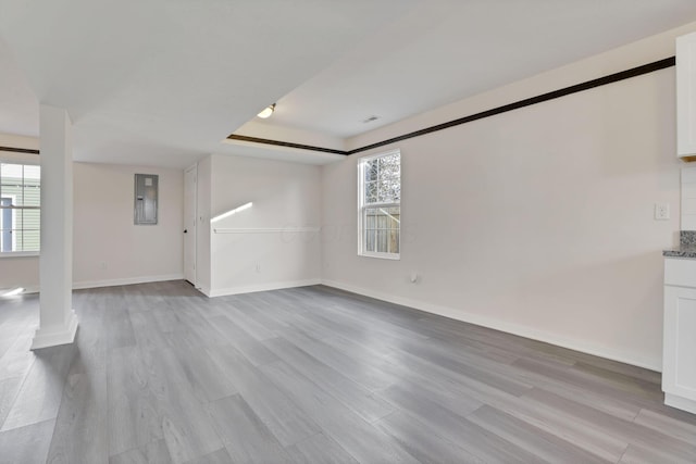 unfurnished living room featuring light wood-style floors, electric panel, and baseboards