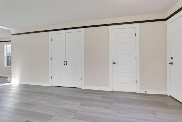 unfurnished bedroom with a barn door, baseboards, and wood finished floors