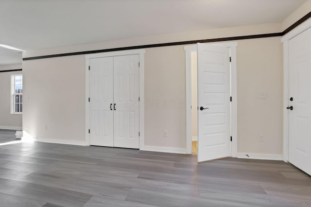 unfurnished bedroom featuring a barn door, wood finished floors, and baseboards