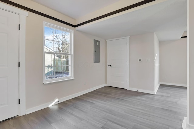 interior space featuring electric panel, baseboards, and wood finished floors