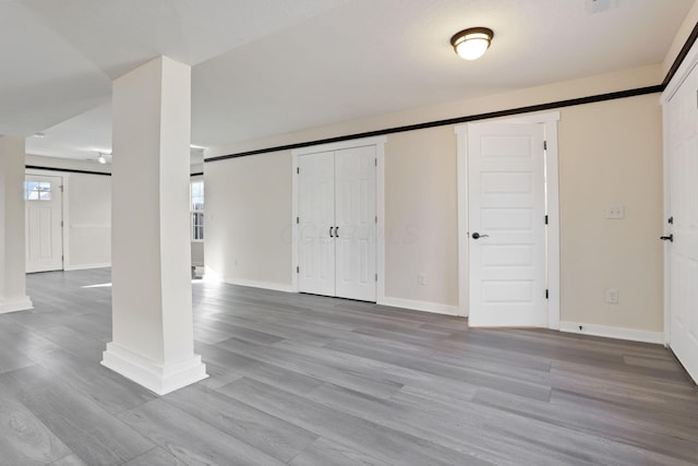 basement featuring a barn door, baseboards, and wood finished floors