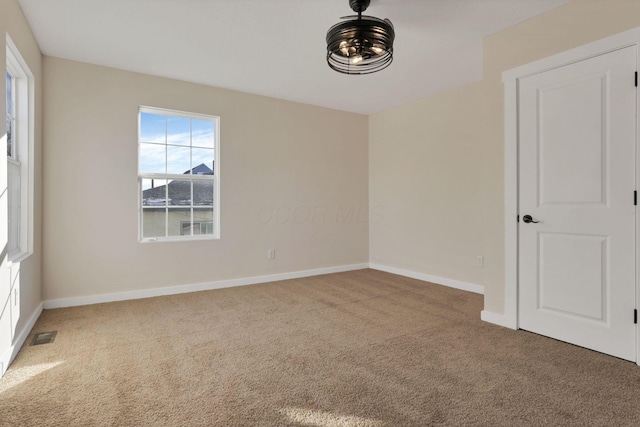 carpeted empty room featuring visible vents and baseboards