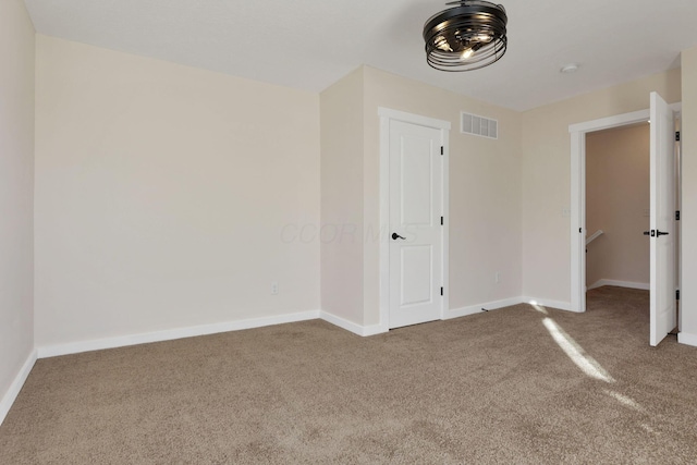 carpeted spare room featuring visible vents and baseboards