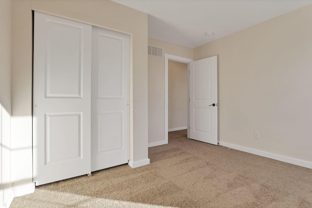 unfurnished bedroom featuring a closet, carpet flooring, visible vents, and baseboards