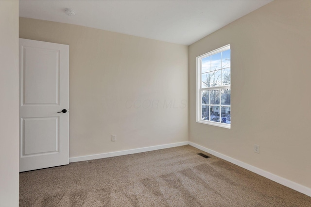 carpeted empty room featuring baseboards and visible vents