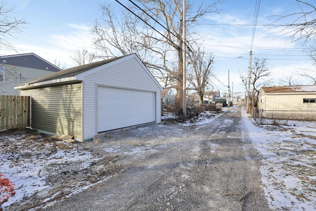 snow covered garage with a garage and fence