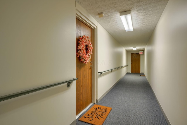 corridor featuring a textured ceiling, carpet, and baseboards