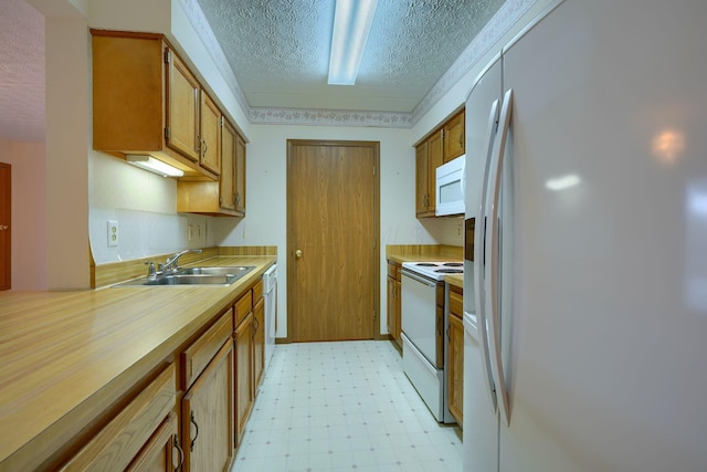 kitchen featuring a textured ceiling, white appliances, a sink, brown cabinets, and light floors