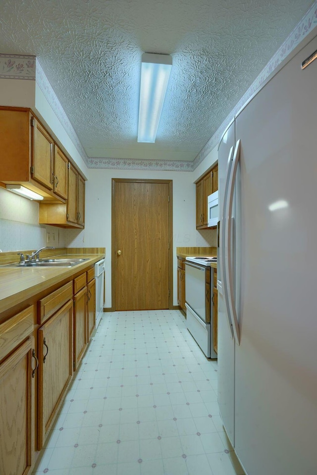 kitchen with brown cabinets, light floors, light countertops, a sink, and white appliances