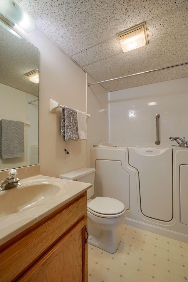 bathroom featuring a drop ceiling, vanity, toilet, and tile patterned floors