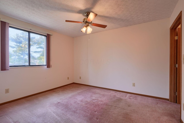 empty room with ceiling fan, a textured ceiling, baseboards, and carpet flooring