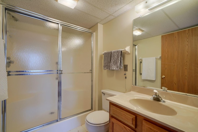 bathroom featuring toilet, a paneled ceiling, vanity, and a shower with door